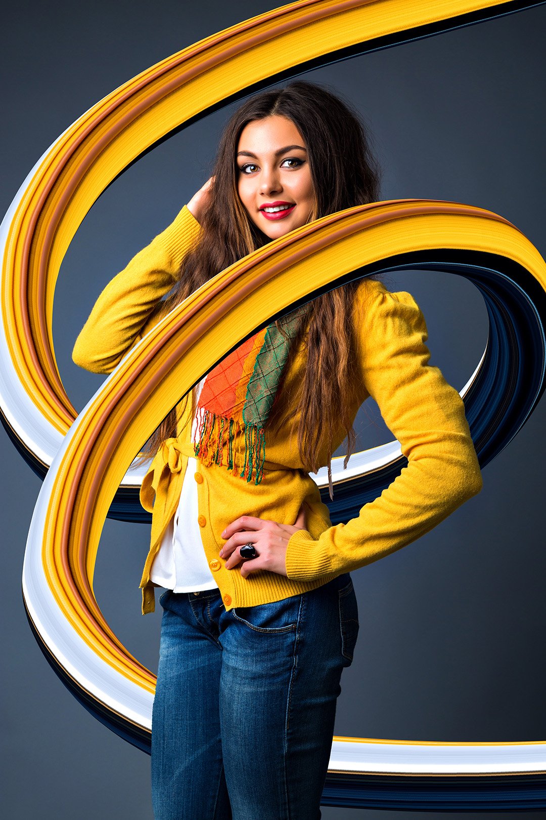 Studio fashion  autumn winter portrait of pretty brunette woman, with a,axing long hairs, bright make up, stylish cozy sweater and scarf, playful mood, gray background, toned colors.